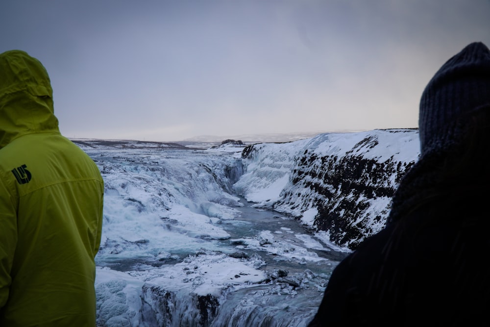 a couple of people standing on top of a snow covered slope