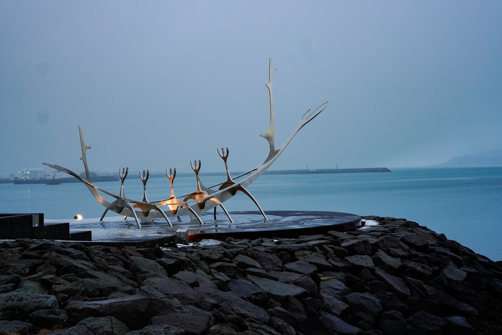 a statue of a group of birds standing on top of a body of water