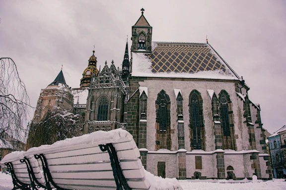 a bench covered in snow in front of a church