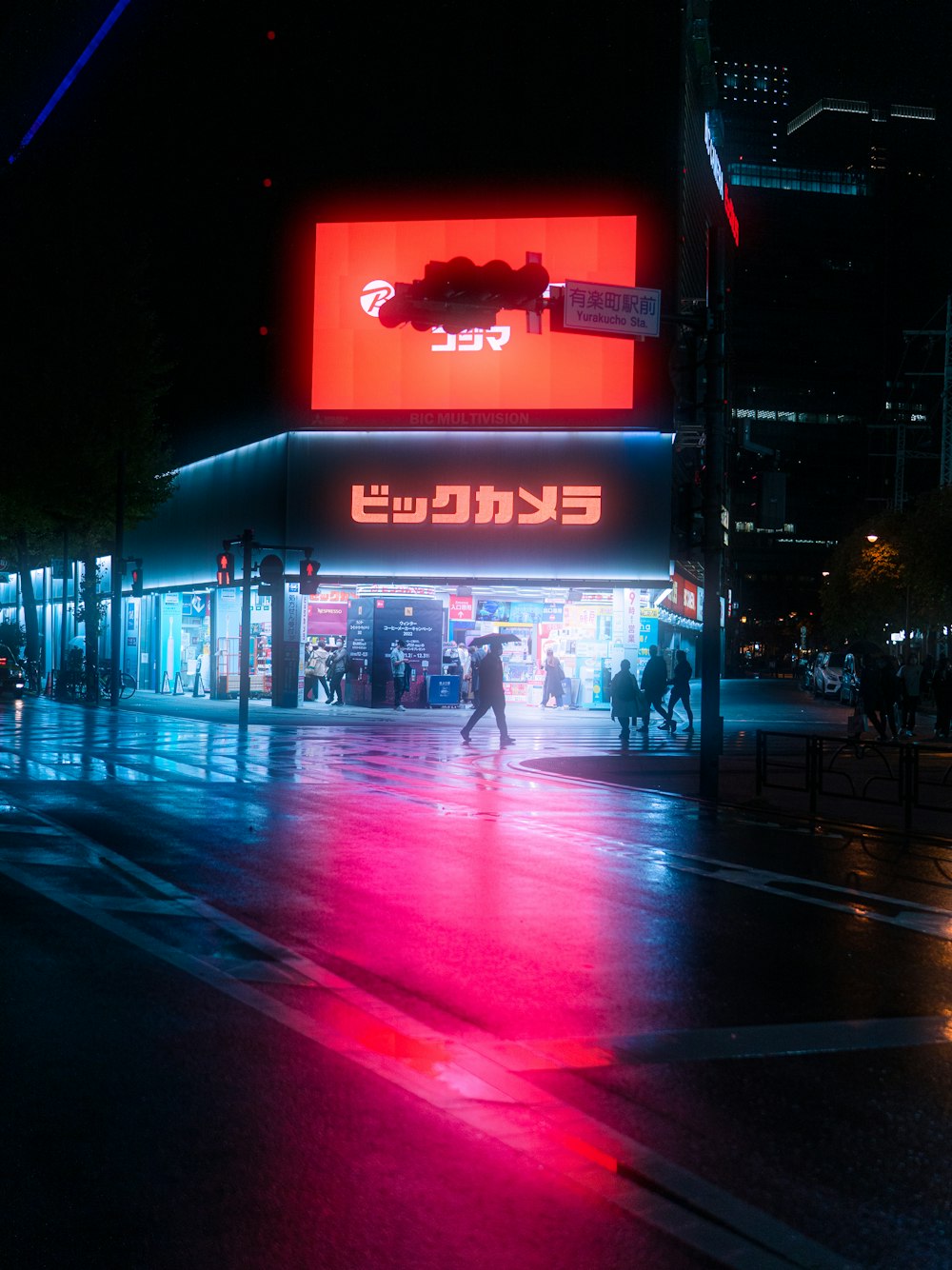 a city street at night with people walking on the sidewalk