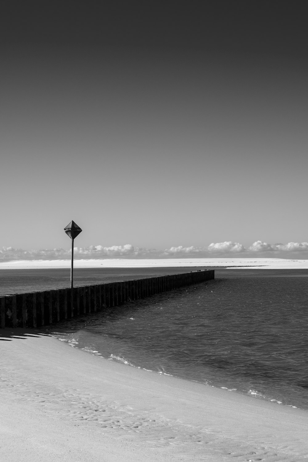 a black and white photo of the ocean and a pier