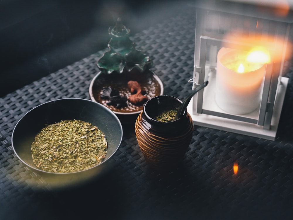a candle and a bowl of herbs on a table