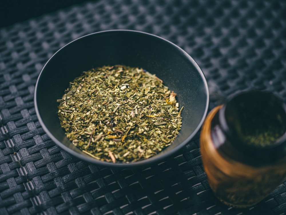 a bowl filled with green tea next to a bottle