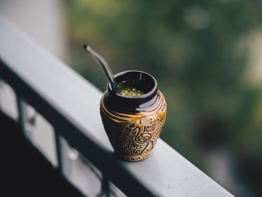 a cup with a straw in it sitting on a ledge