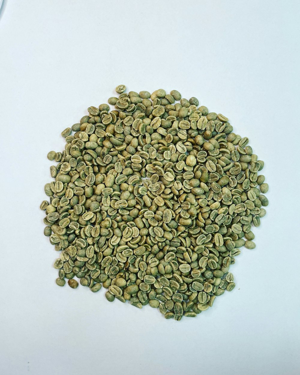 a pile of green coffee beans sitting on top of a white table