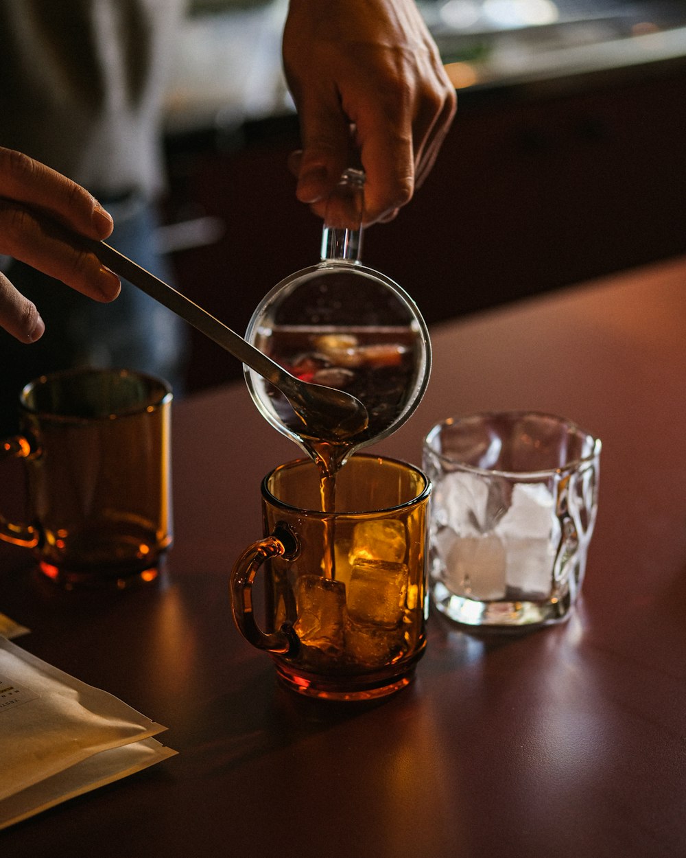 a person pours tea into a glass mug