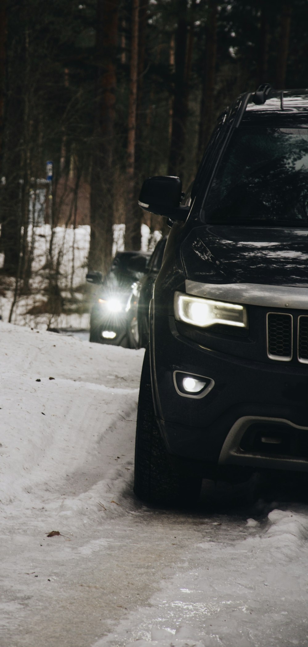 a black jeep driving down a snow covered road