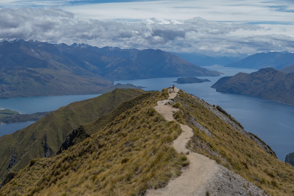 a trail going up a mountain with a lake in the background