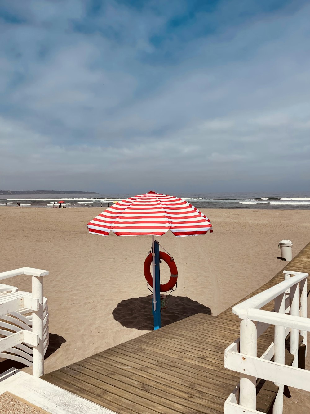해변 꼭대기에 앉아있는 빨간색과 흰색 우산