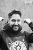 A model smiling warmly while wearing a hoodie with a scripture verse printed on the sleeve.