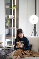 A cozy indoor scene with a woman relaxing in a modern living room wearing a rosaslins sweatshirt.