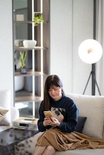 A stylish woman browsing the website on a smartphone in a cozy setting.