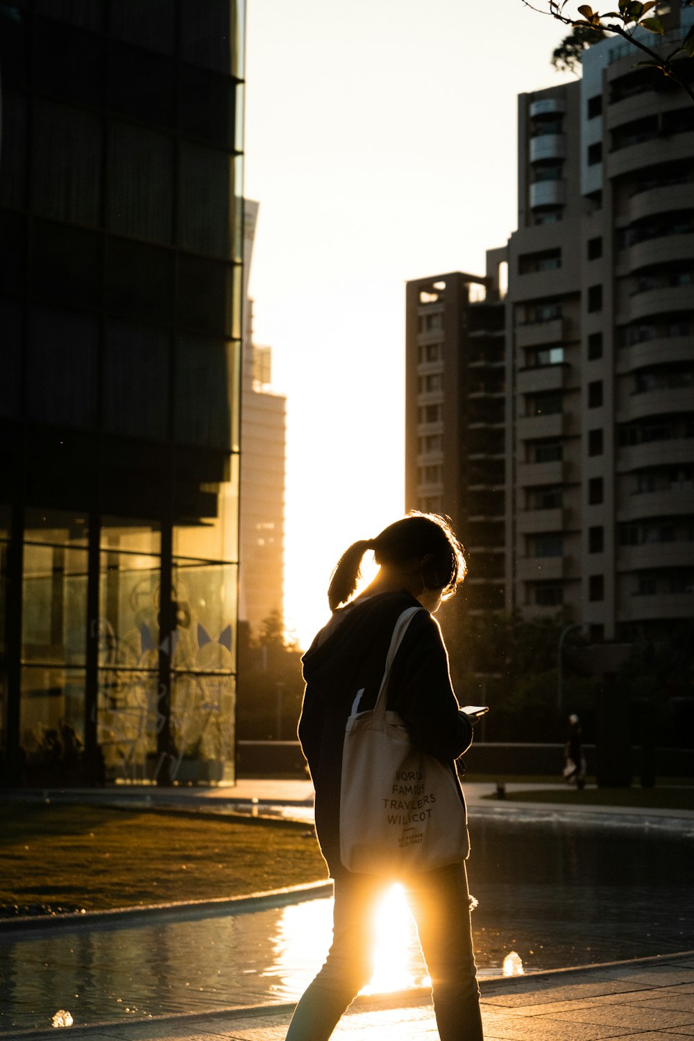 a woman walking down a street next to tall buildings