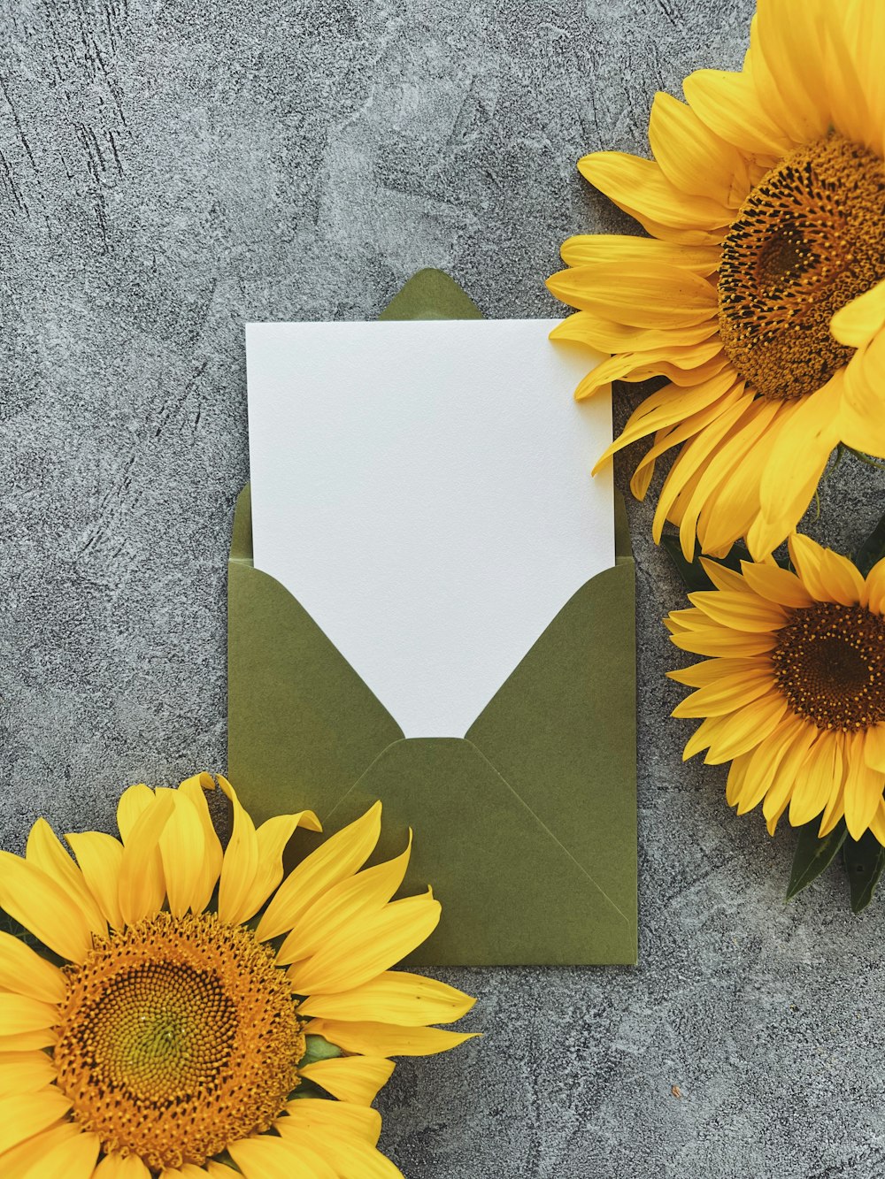 Sonnenblumen und ein Umschlag auf einer Betonoberfläche