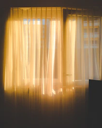 a window with sheer curtains and a television