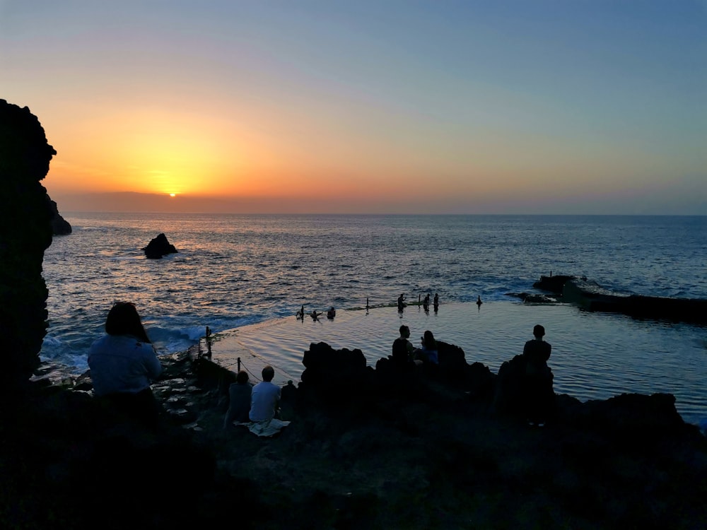 a group of people standing on top of a beach next to the ocean