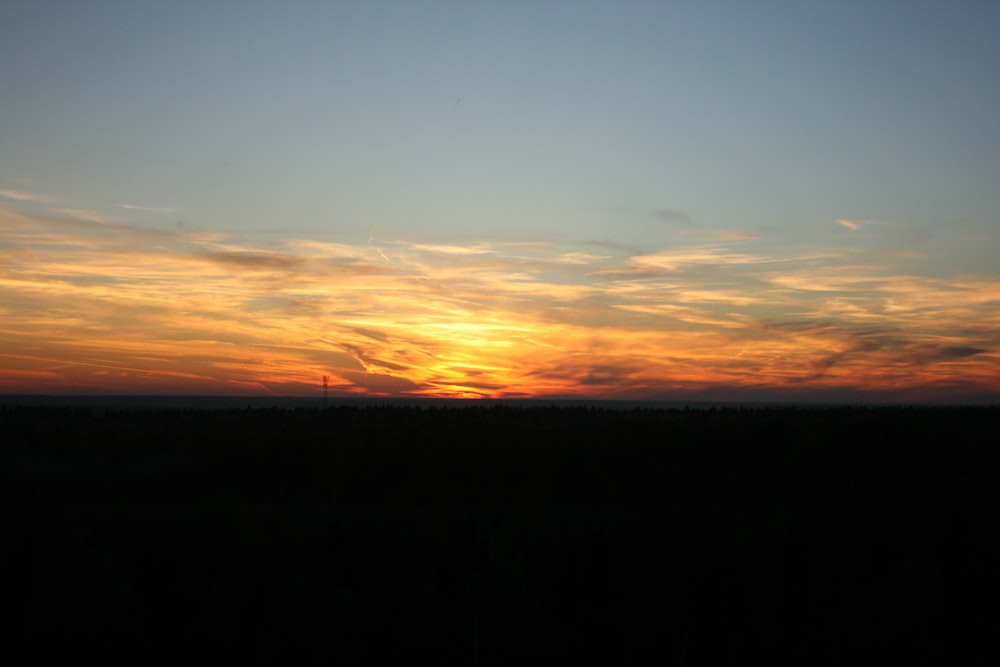 the sun is setting over the horizon of a field