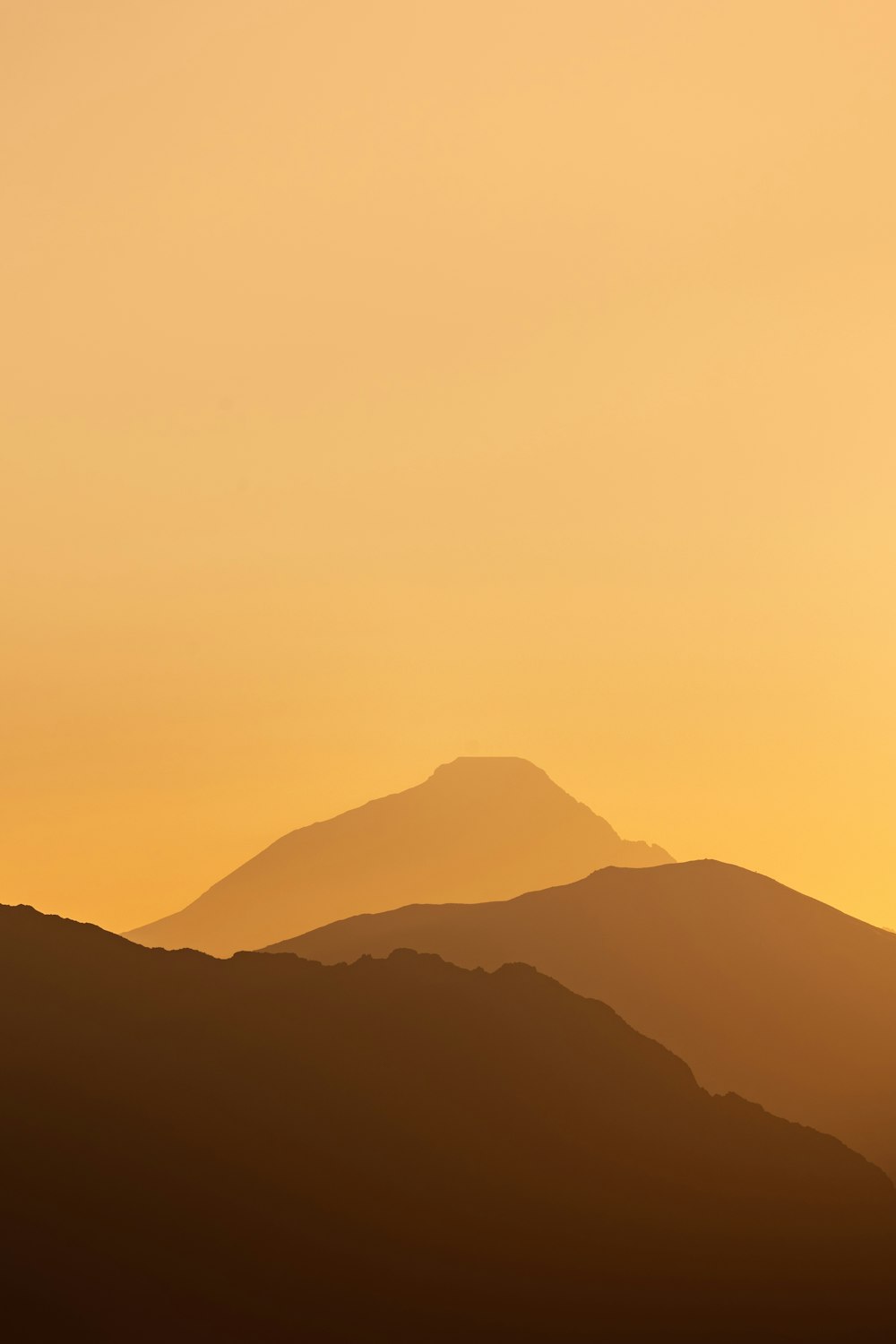 a plane flying over a mountain range at sunset