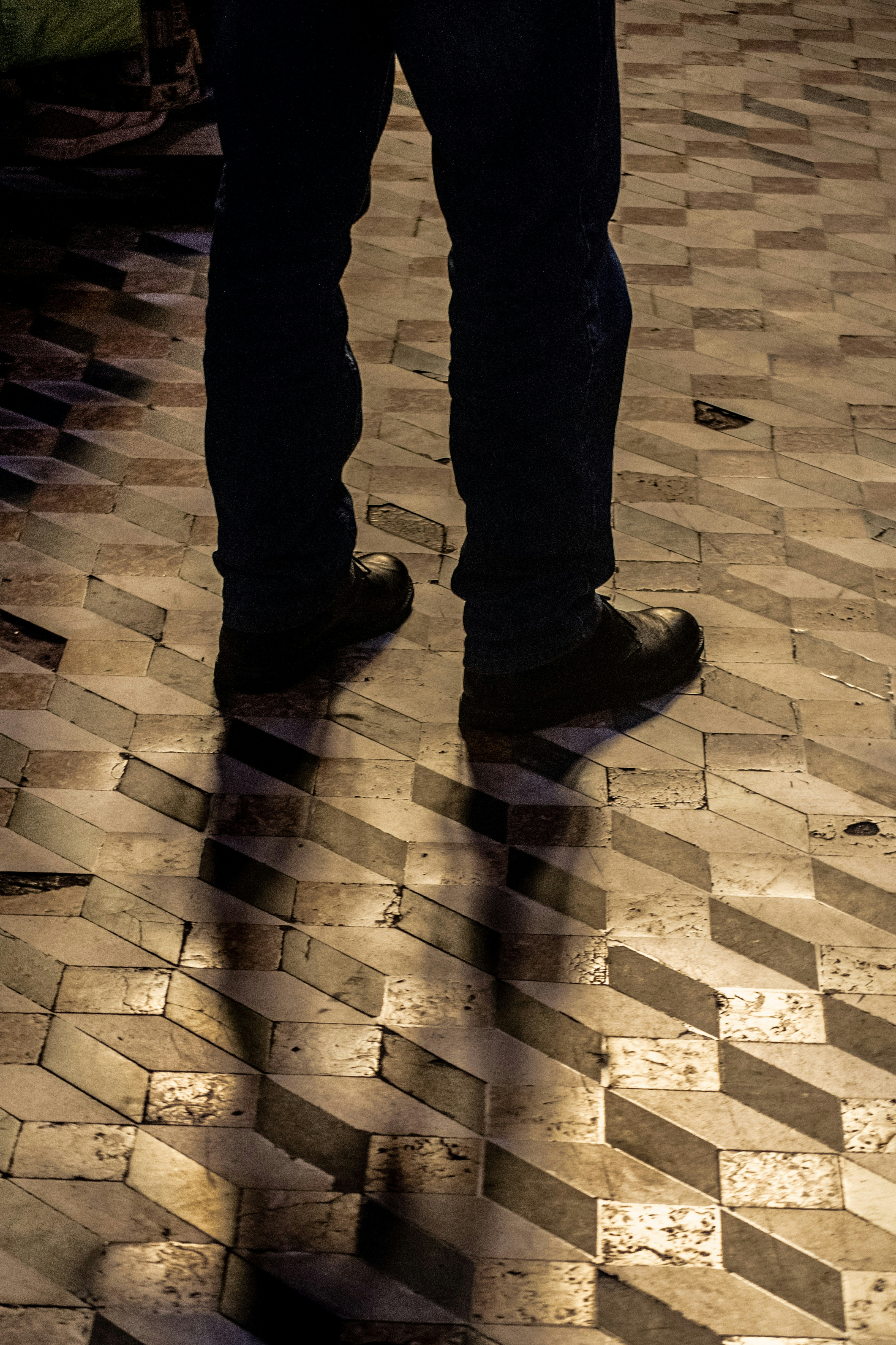 a person standing on a tiled floor with their shadow on the ground