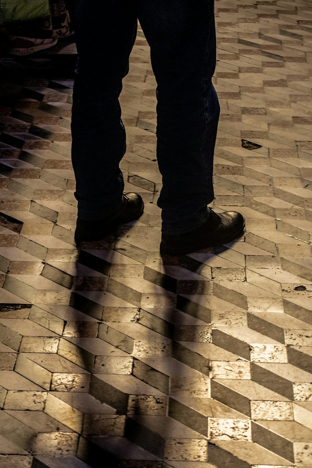 a person standing on a tiled floor with their shadow on the ground