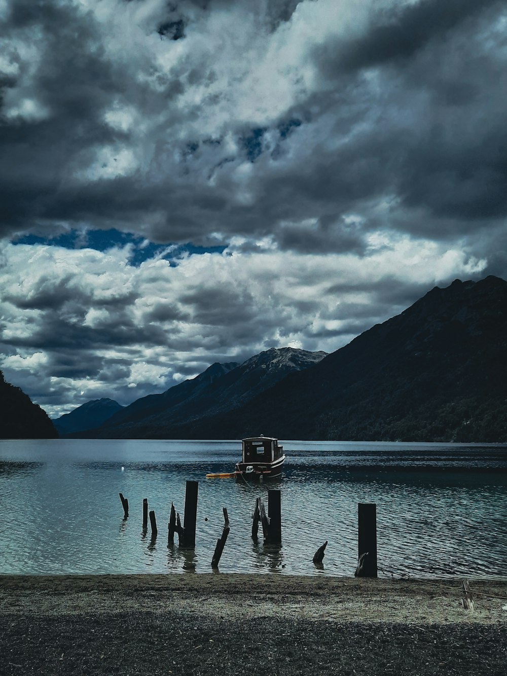 a boat sitting on top of a lake under a cloudy sky