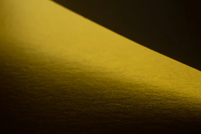 A gradual transition from dark shadows to warm golden light streaming softly across a textured surface.