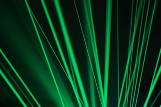 Bright green laser beams shining through a dark background and creating a dynamic, energetic pattern.