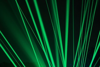 Bright green laser beams shining through a dark background and creating a dynamic, energetic pattern.