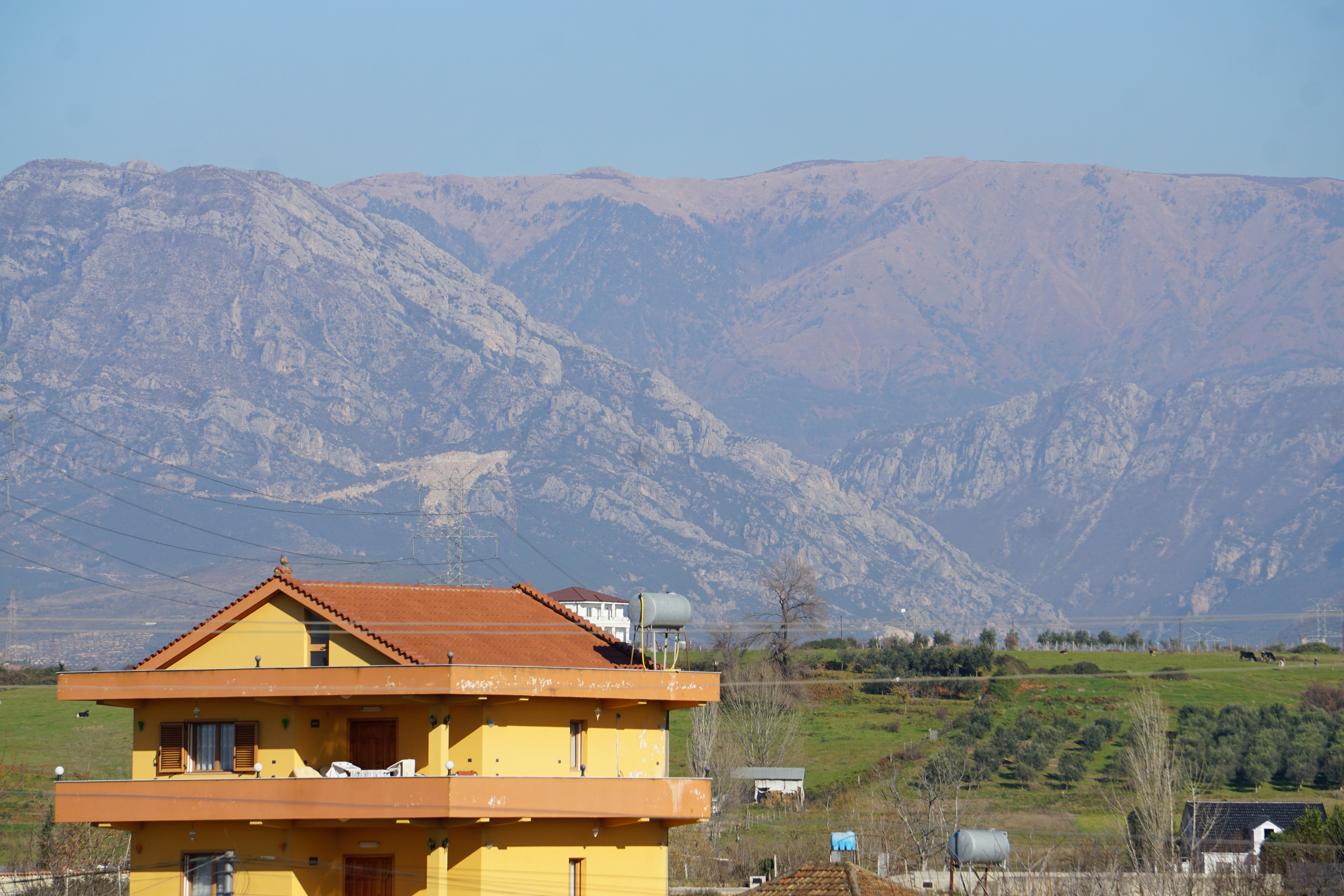 a yellow house with mountains in the background