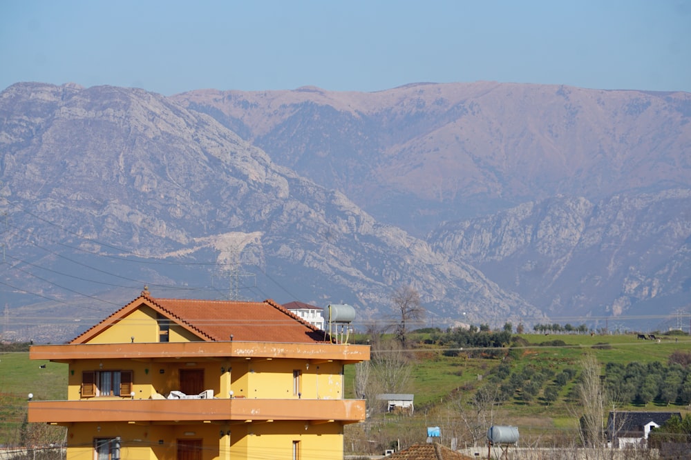 a yellow house with mountains in the background