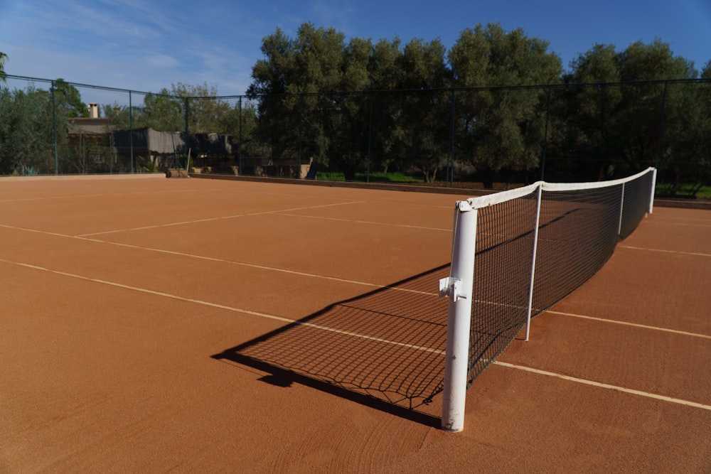 una pista de tenis con una red de tenis y árboles al fondo