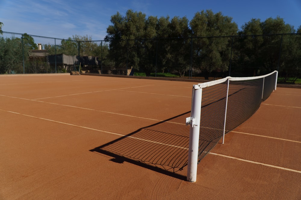 a tennis court with a tennis net and trees in the background