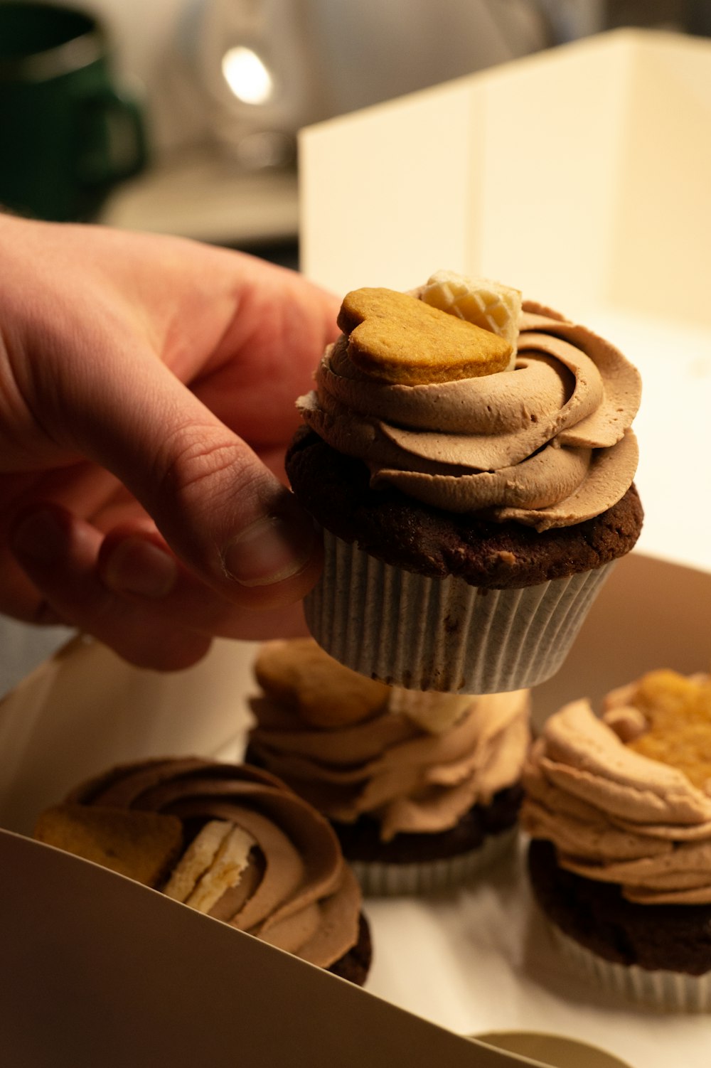 a person is picking up a cupcake from a box