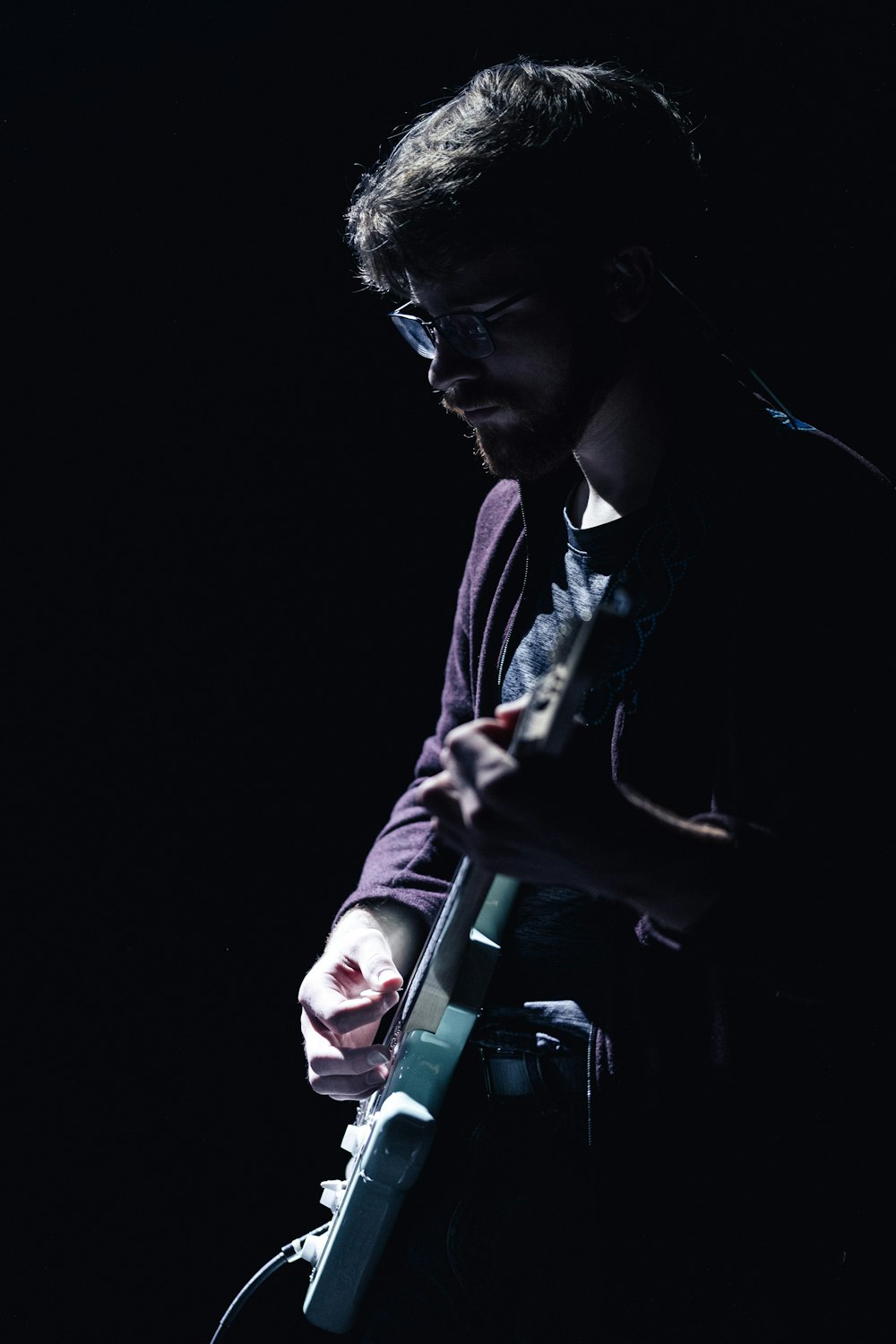 a man playing a guitar in the dark