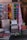 A display of colorful woven textiles in various patterns and colors is arranged against a backdrop. The textiles include stripes and solid colors, suggesting they are artisanal blankets or rugs. One piece features a smiling face design, and there are several folded textiles stacked below.