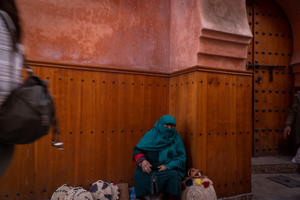 a woman sitting on the ground in front of a building