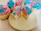 Close-up of colorful pastel cupcakes arranged on a pastel-colored table with soft lighting.