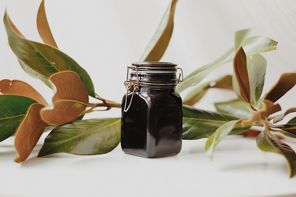 a jar of black liquid sitting on top of a table