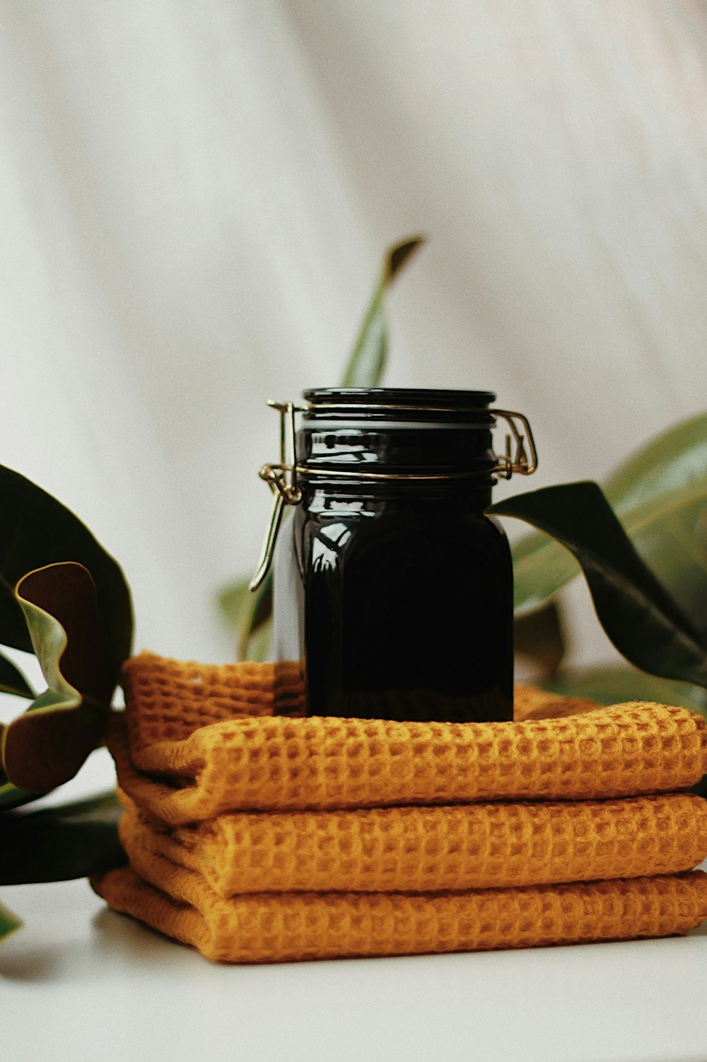 a jar of liquid sitting on top of a stack of yellow towels