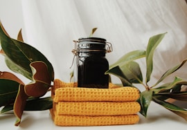 a jar of liquid sitting on top of a stack of yellow towels