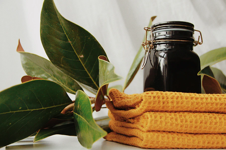 A dark glass jar among green leaves on a folded towel