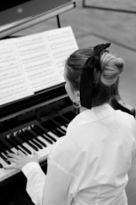 a woman in white shirt playing a piano