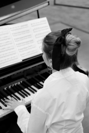 a woman in white shirt playing a piano