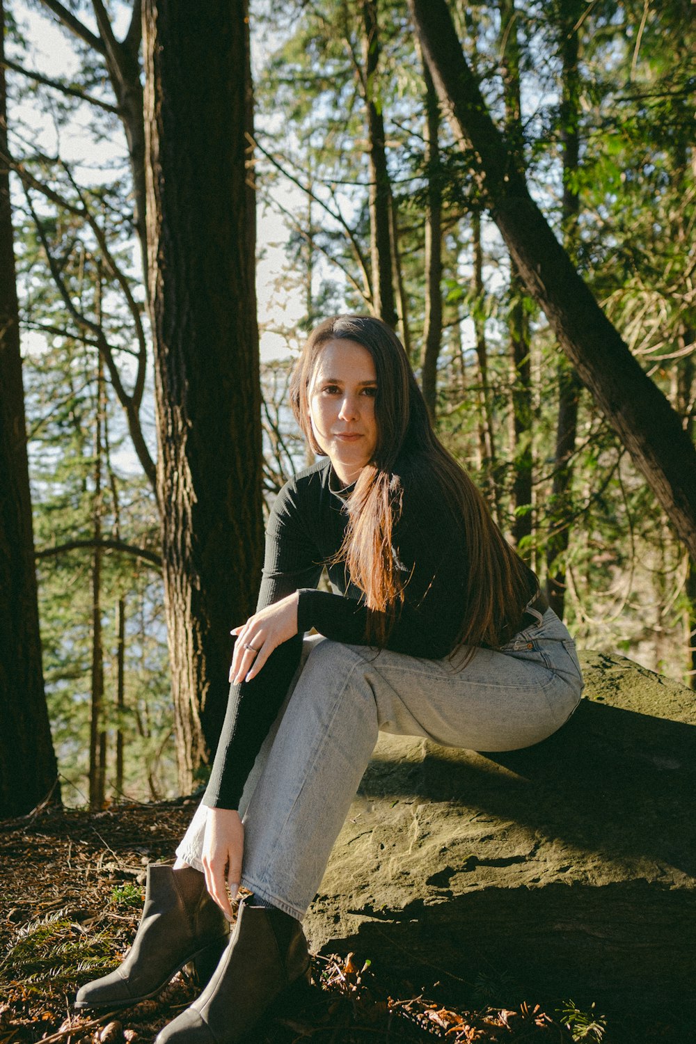 a woman sitting on a rock in the woods