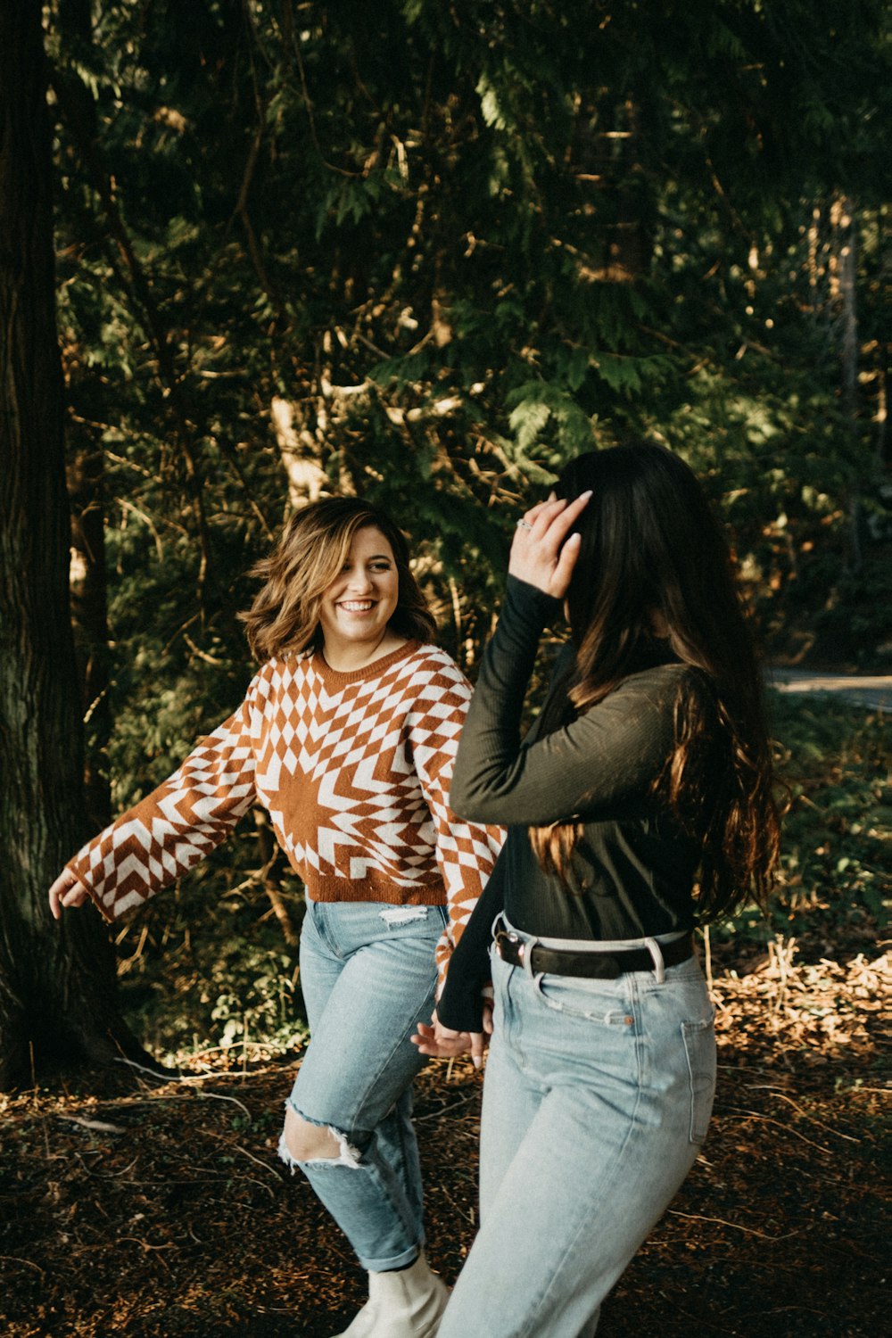 two women standing next to each other in the woods