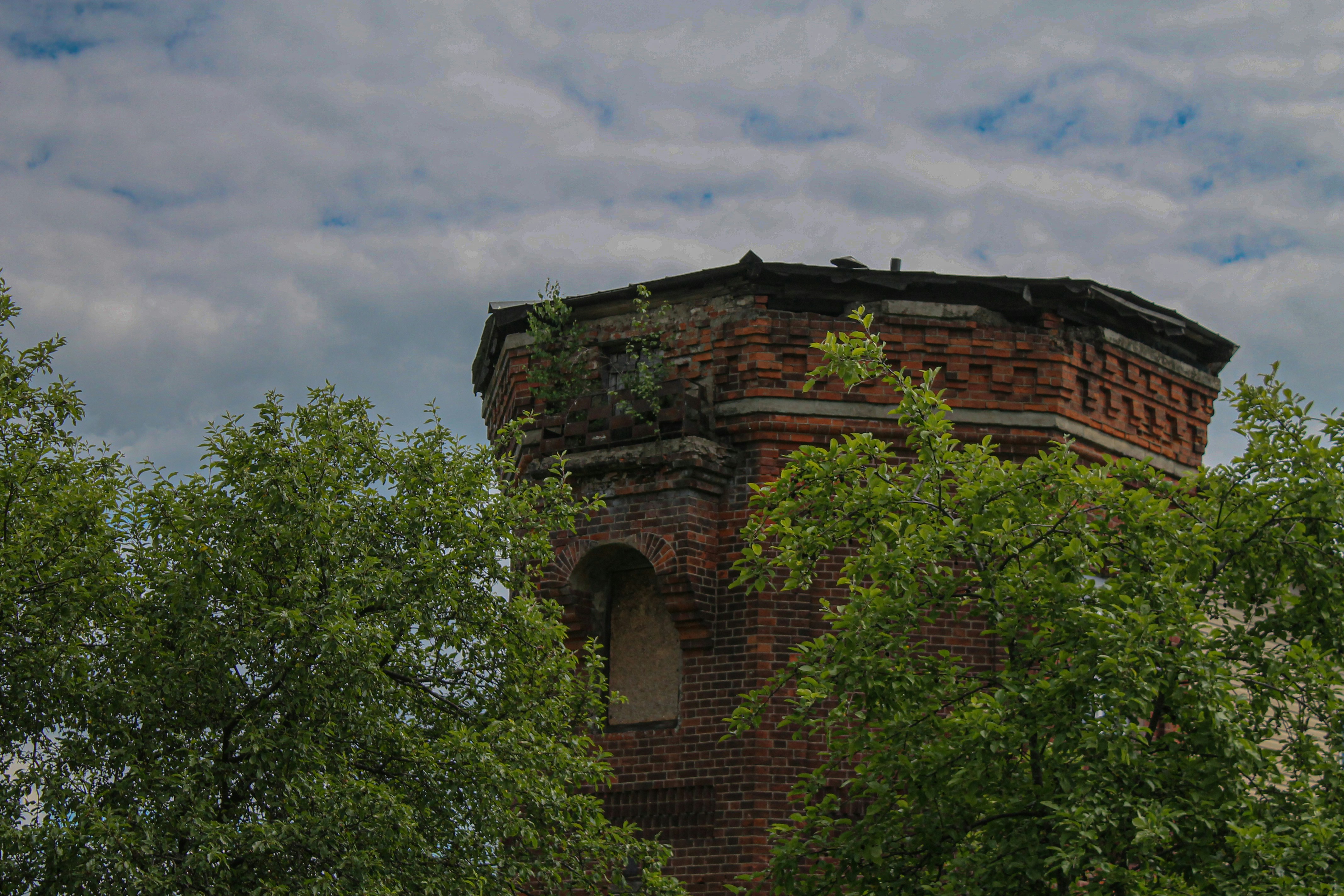 a brick tower surrounded by trees under a cloudy sky