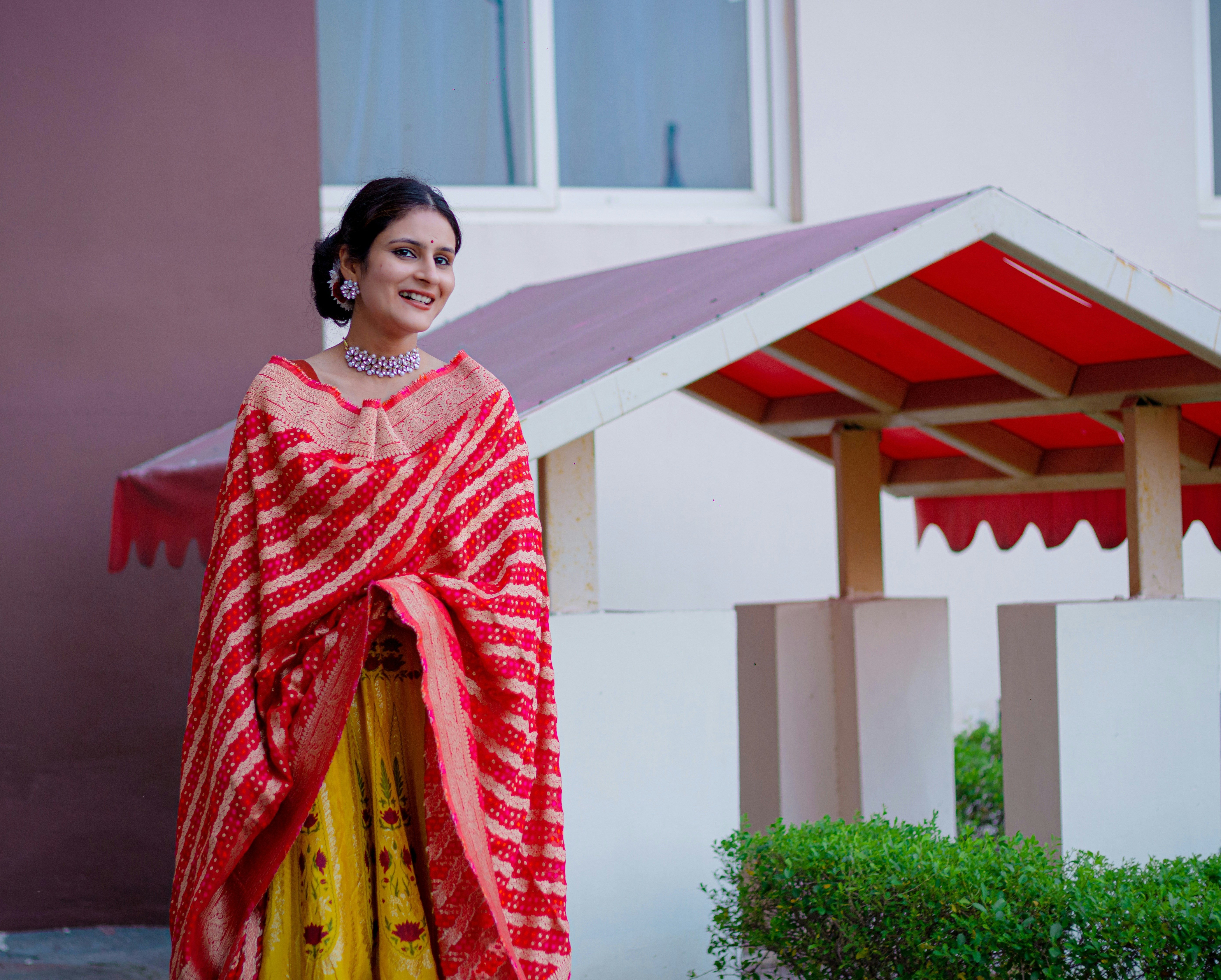 Indian woman smiling warmly, colorful traditional clothing, outdoor setting