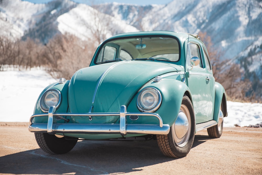 a blue car parked in front of a mountain