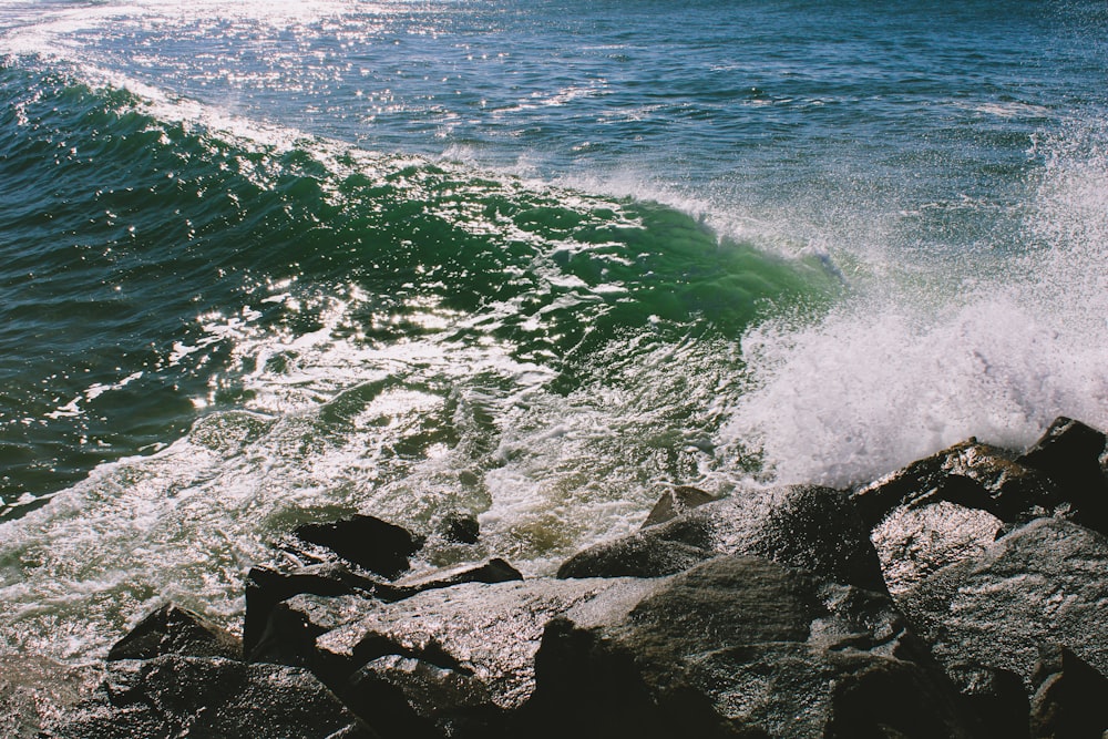 a wave crashes on the rocks near the shore