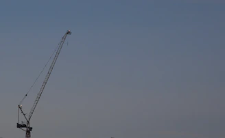 A sleek articulated boom lift extending high against a clear blue sky.